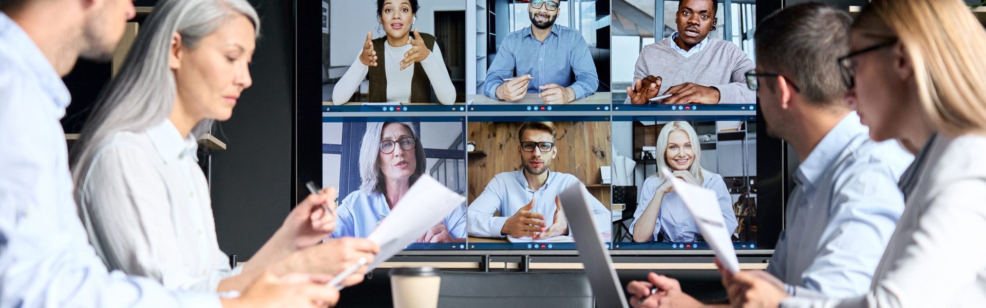 Global corporation online videoconference in meeting room with diverse people sitting in modern office and multicultural multiethnic colleagues on big screen monitor. Business technologies concept.